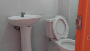 A small bathroom with a white sink and toilet. - WJV INN NAGA (Naga City)