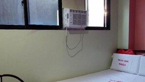 A single-bed room with a window, a wall-mounted air conditioner, and a red chair. - WJV INN NAGA (Naga City)