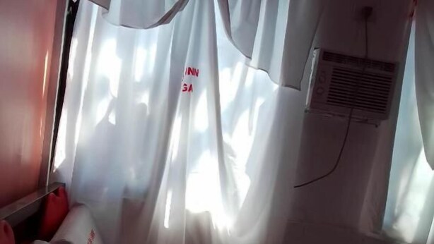 A hotel room with a bed, white curtains, and a window with a view. - WJV INN NAGA (Naga City)