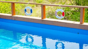 Ein Schwimmbecken mit zwei Rettungsringen, die an einem hölzernen Geländer hängen.