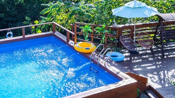 Una terraza de madera con piscina, sillas de descanso y un flotador.