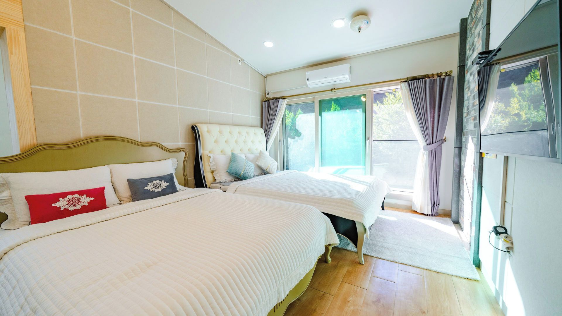 Un dormitorio con dos camas, una ventana con cortinas y una puerta que da a un espacio exterior.