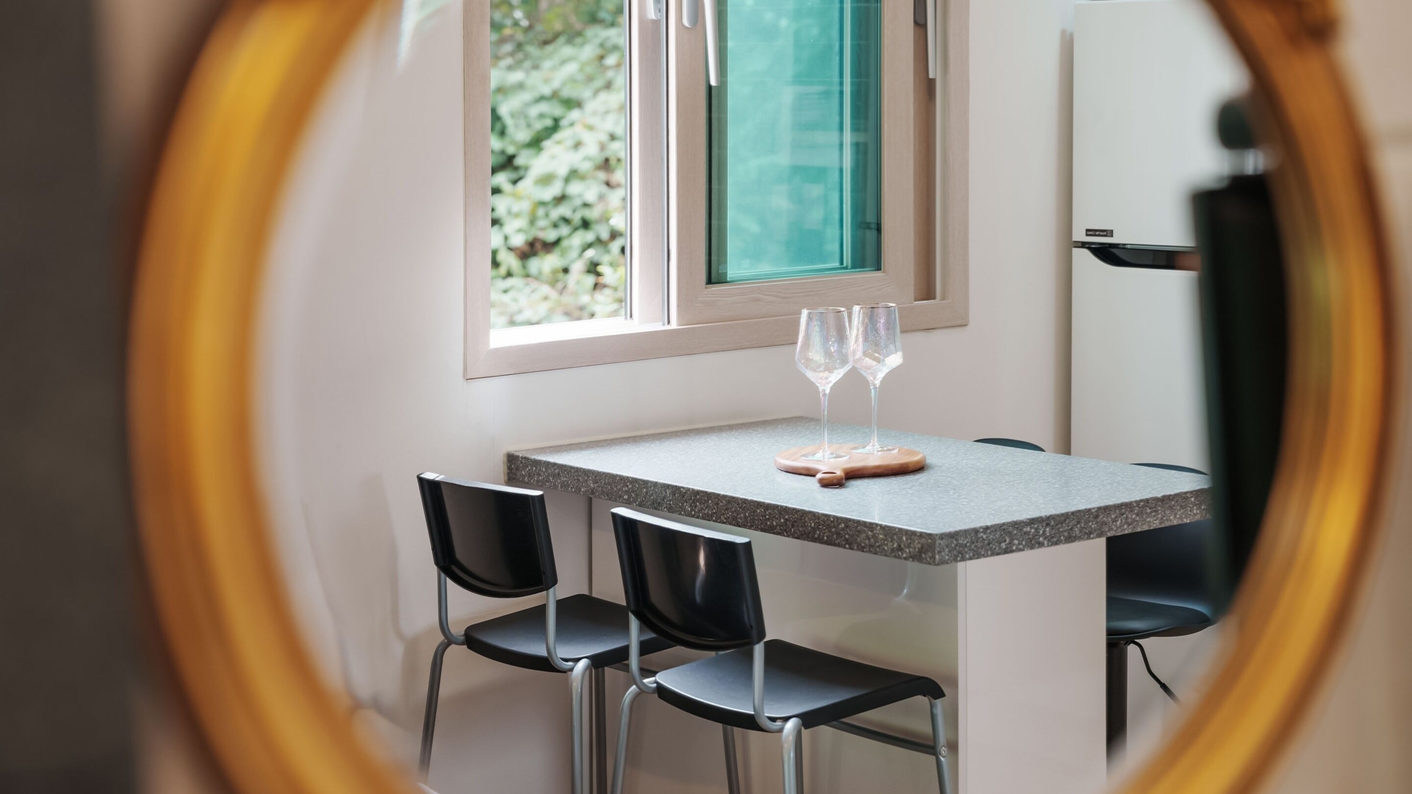 Uma sala de jantar com uma mesa, duas cadeiras e dois copos de vinho.