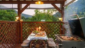 An outdoor patio with a grill, a table set for a meal, and a view of a forested area. - Gapyeong Pinenut Pension (Gapyeong)