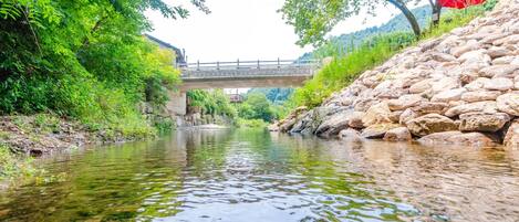 A river with a stone wall on one side and a bridge in the background.