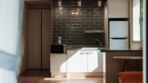 Une cuisine moderne avec un dosseret de carreaux noirs, des meubles blancs et un micro-ondes encastré.