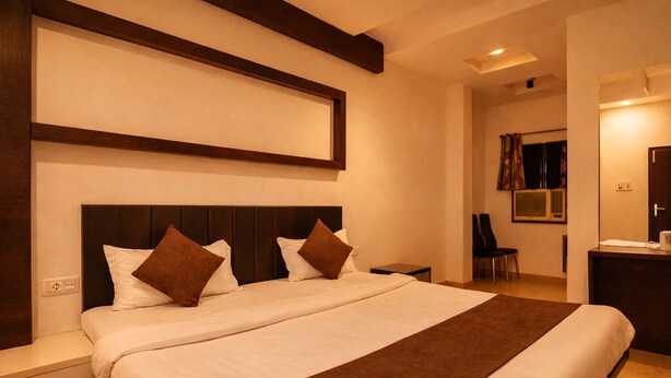 Een moderne hotelkamer met een groot bed, een donker houten hoofdeinde en een bruin decoratief vloerkleed.