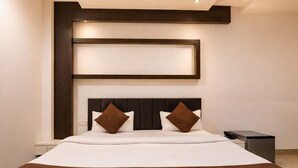 Een moderne hotelkamer met een groot bed, een donker hoofdeinde en twee kussens.
