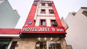 Een hotel genaamd 'HOTEL JUST 9 inn' met een rode en witte gevel, meerdere ramen en een duidelijke ingang.