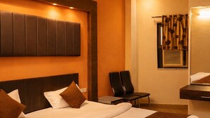 Hotelkamer met een groot bed, een plafondventilator, een zithoek met stoelen en een kleine tafel.