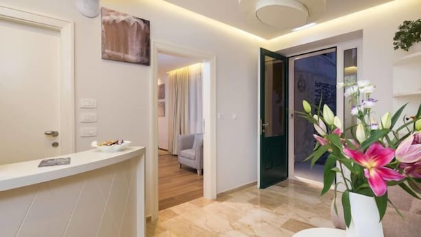 Eine moderne Hotellobby mit einer Rezeption, einem Blumenstrauß und Blick in einen Wohnbereich.