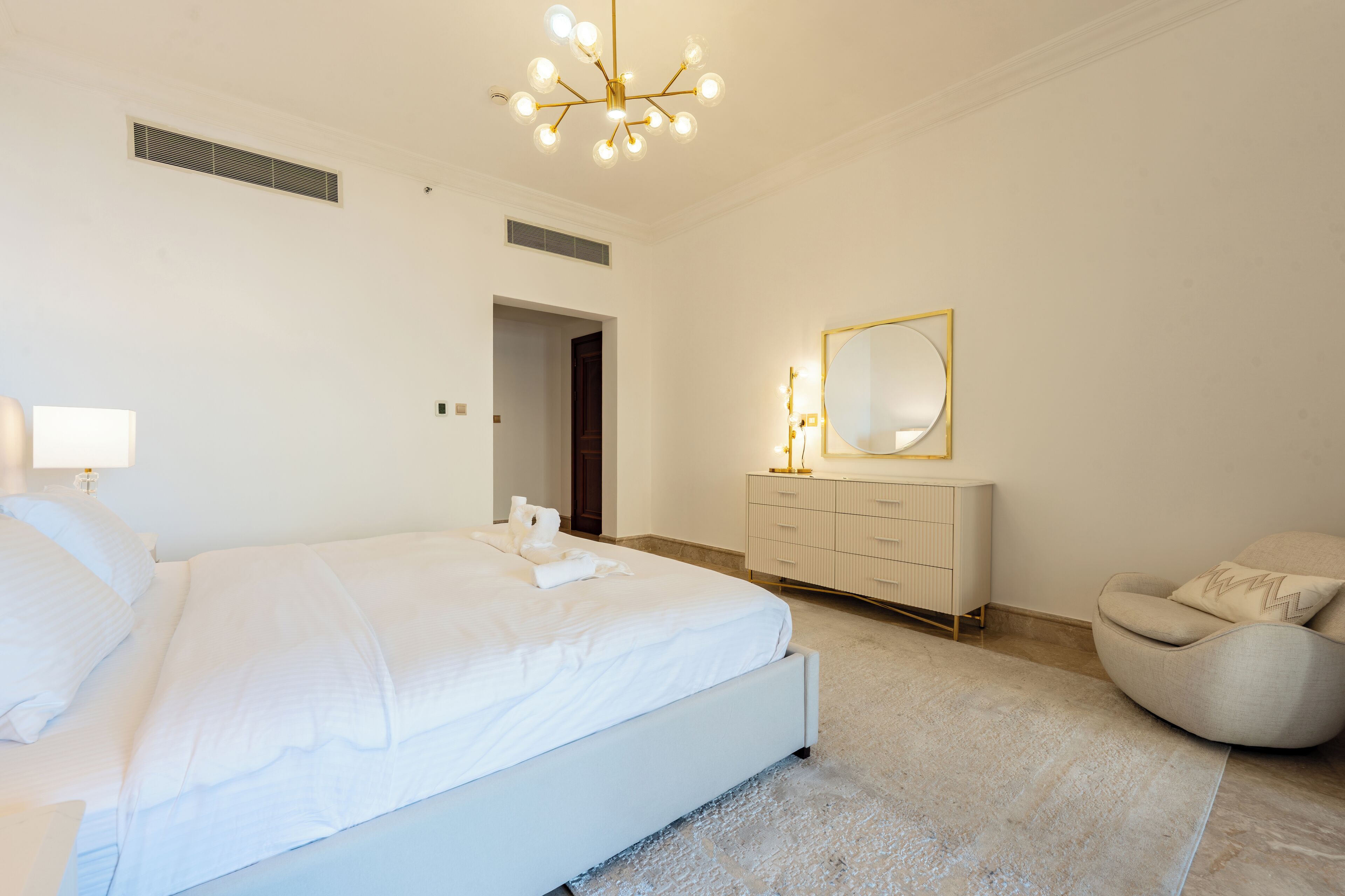 Une chambre moderne avec un grand lit, une coiffeuse avec un miroir et une chaise.