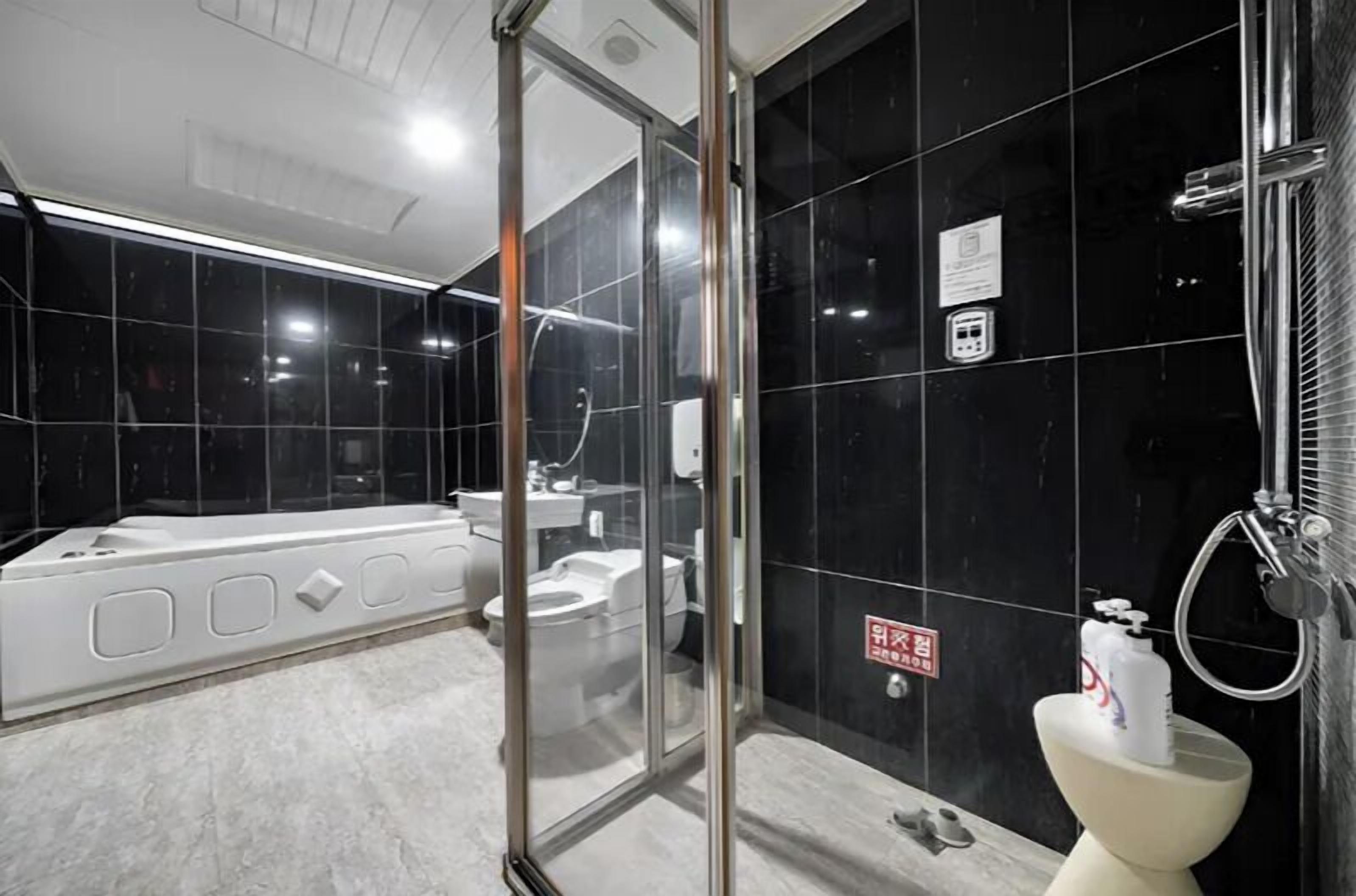 A modern bathroom with a glass shower enclosure, a toilet, and a bidet.
