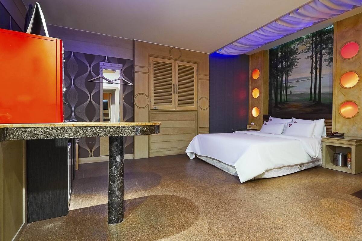A bedroom with a bed, a desk, and a chair.