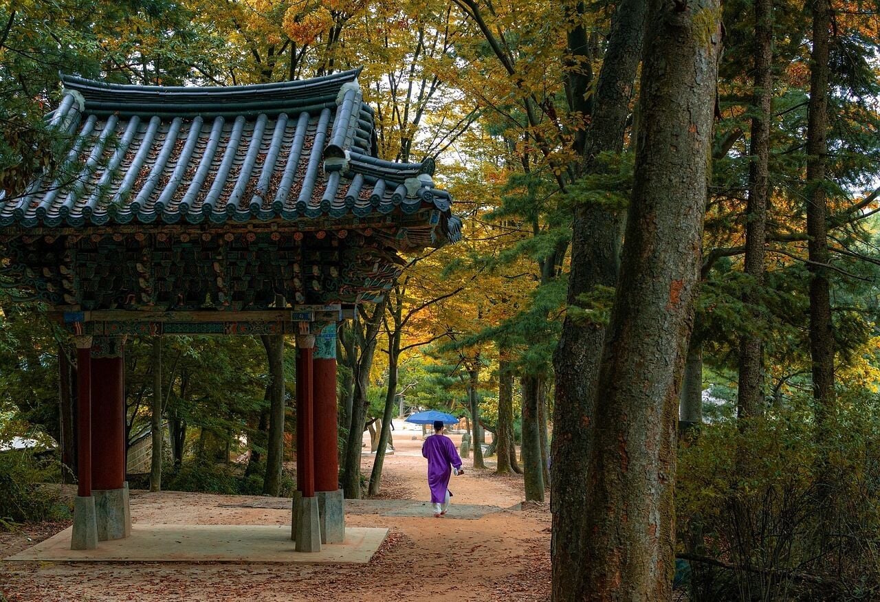 Un pavillon traditionnel, doté d’un toit en tuiles, entouré d’arbres et bordé d’un sentier.