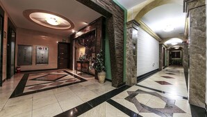 A modern hotel lobby with a geometric patterned floor, a reception desk, and an elevator. - From H Amoremio The Classic Suwon (Suwon)