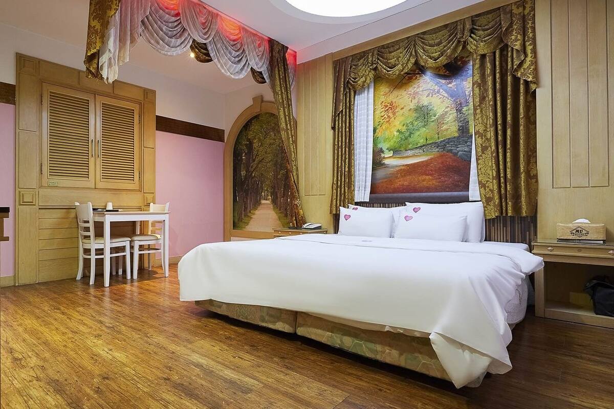 A bedroom with a bed, a desk, and chairs.