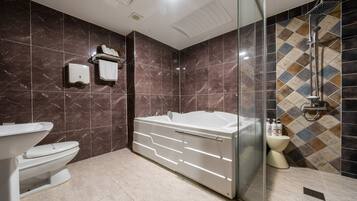 Une salle de bain moderne avec une baignoire sur pieds, des toilettes et une douche séparée par des parois en verre.