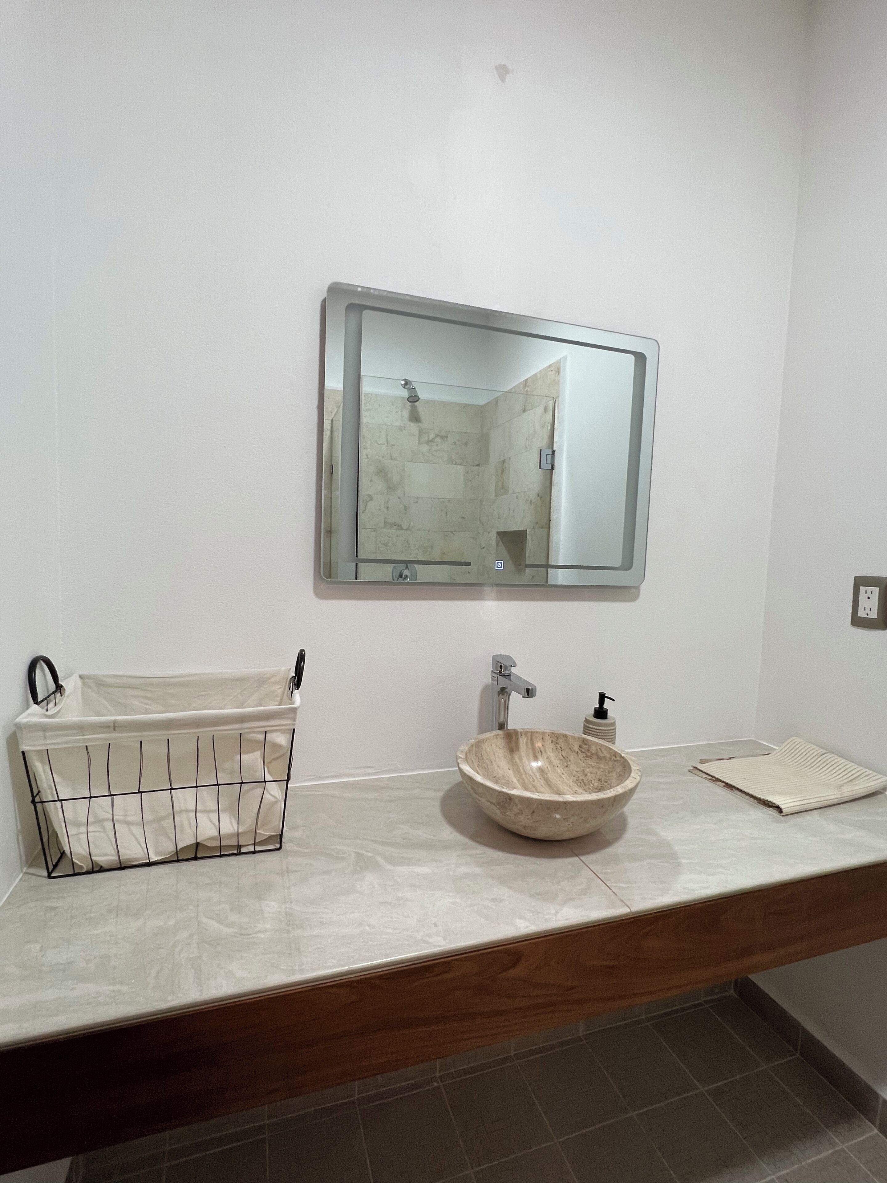 Un baño con un espejo grande, un lavabo y una ducha.