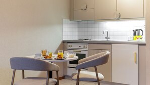 A small kitchenette with a dining area, including a table with chairs, a kettle, and a toaster.