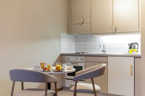 Una pequeña kitchenette con comedor, que incluye una mesa con sillas, una tetera y un tostador.