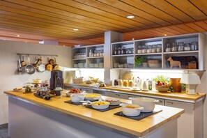 Una cocina con encimeras de madera, estantes con frascos y ollas colgantes.