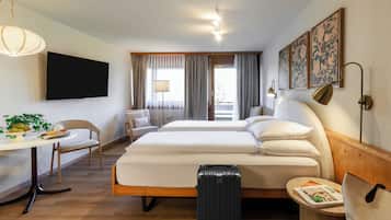 Une chambre d’hôtel avec un lit, un bureau, une chaise, une valise et un téléviseur.