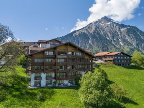 A multi-story hotel with balconies, set against a mountainous backdrop. - Hotel Aeschi Interlaken - Handwritten Collection (Aeschi bei Spiez)