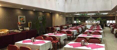 Un comedor amplio con múltiples mesas y sillas, un techo alto con tragaluces y un pasillo central.