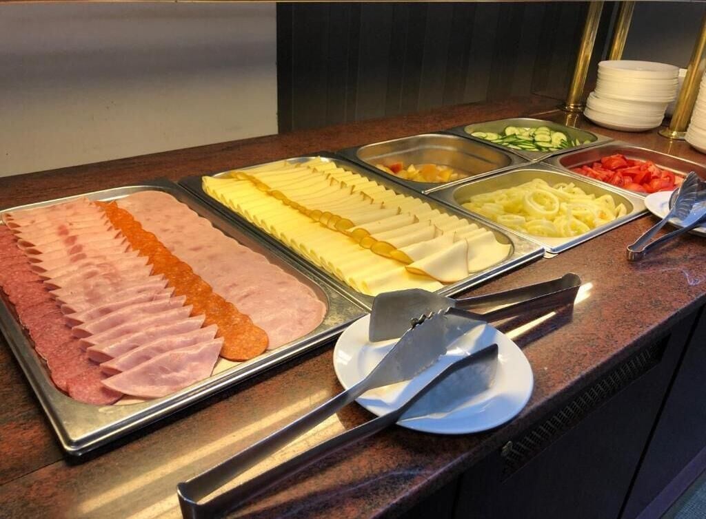 A buffet with various food options including sliced meats, cheeses, and vegetables.