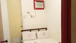 A hotel room with a bed, a door, a vent, and a wall-mounted air conditioner. - WJV INN MANDAUE CENTRO (Mandaue)
