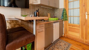 Eine kleine Küche mit Fernseher, Holztür und einem gemusterten Teppich.