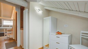 Une pièce dotée d’un plancher en bois, de meubles blancs, d’un radiateur et d’un plafond avec des poutres apparentes.