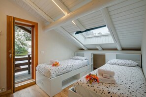 A room with two beds, a skylight, and a door leading to a balcony.