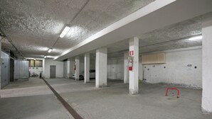 Un parking souterrain avec des piliers en béton, des places de stationnement numérotées et un extincteur rouge.