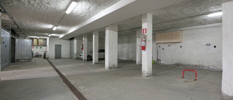 Eine Parkgarage mit Betonpfeilern, nummerierten Stellplätzen und einem roten Feuerlöscher.