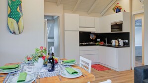 A modern kitchen with white cabinets, a black countertop, and a dining area with a wooden table set for four.