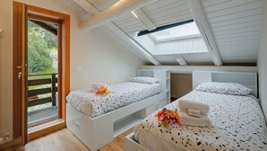 Une chambre avec deux lits, une lucarne et une porte en bois donnant sur un espace extérieur.