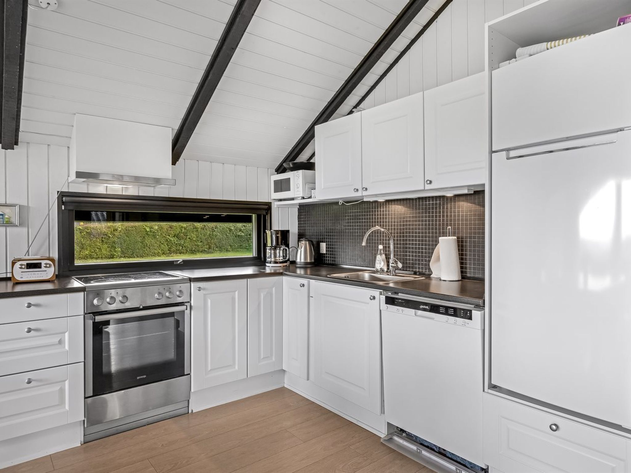 A modern kitchen with white cabinets, stainless steel appliances, a built-in oven, a microwave, and a dishwasher.