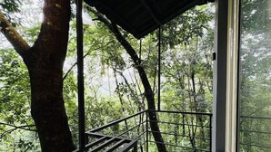 A balcony with a metal railing overlooking a forested area. - Vayalada Garden resort (Koyilandy)
