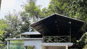 A modern house with a covered garage, a motorcycle, and a car parked inside. - Vayalada Garden resort (Koyilandy)
