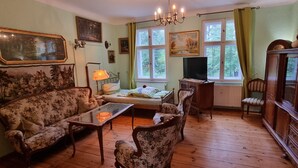 Een klassieke kamer met een bank, fauteuil en een houten kast.