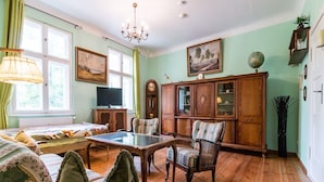 Een kamer met een bed, een televisie, een houten kast en een kroonluchter.