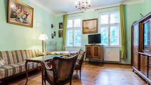 Een kamer met een bank, eettafel, stoelen, een televisie en een kast.