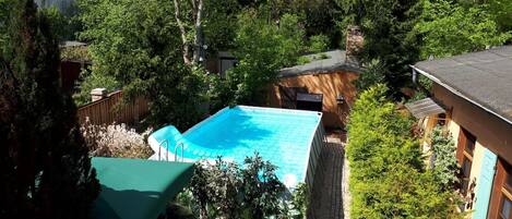 A backyard with a swimming pool, surrounded by trees and a small shed.