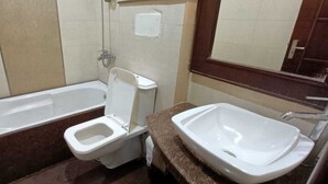 A bathroom with a bathtub, a toilet, and a sink. - Roomshala Hotel J JOy (New Delhi)