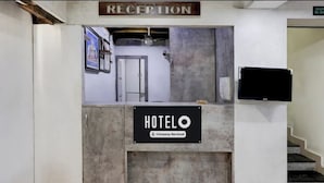 A reception desk labeled "HOTEL" with a sign indicating it is company-serviced. - SRI ADITI INN (Vijayawada)