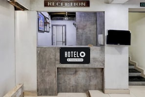 A reception desk labeled "HOTEL" with a sign indicating it is company-serviced. - SRI ADITI INN (Vijayawada)