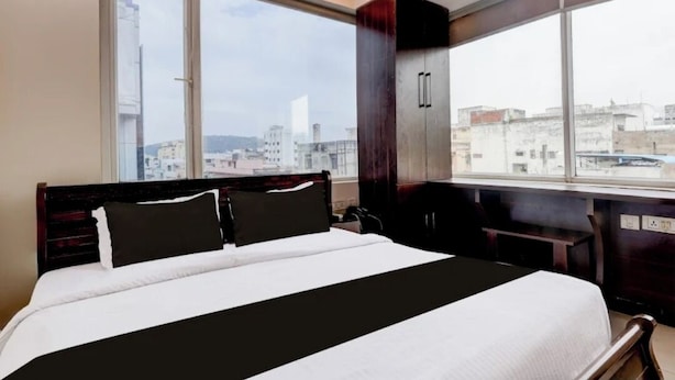 A hotel room with a large bed, a view of the city through a window, and a wardrobe. - SRI ADITI INN (Vijayawada)