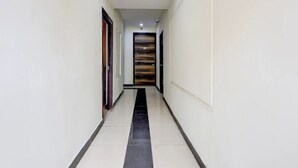 A narrow, well-lit hallway with a tiled floor and a wooden door at the end. - SRI ADITI INN (Vijayawada)